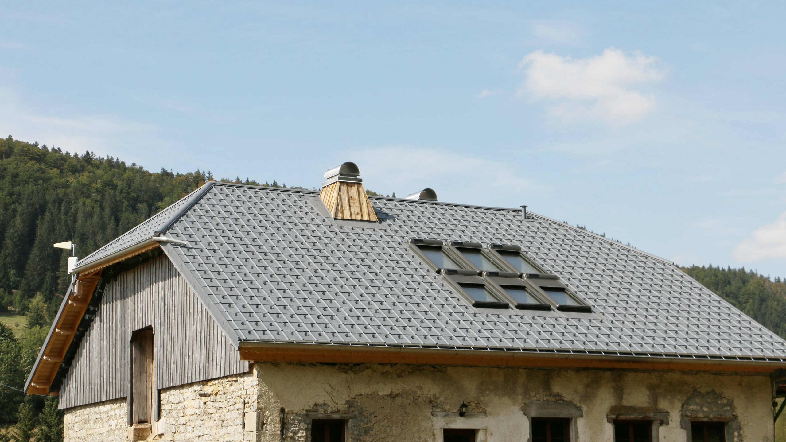 Vue rapprochée de ce chalet dont la couverture a été rénovée avec les tuiles en aluminium prefa choisies dans la teinte P.10 gris pierre