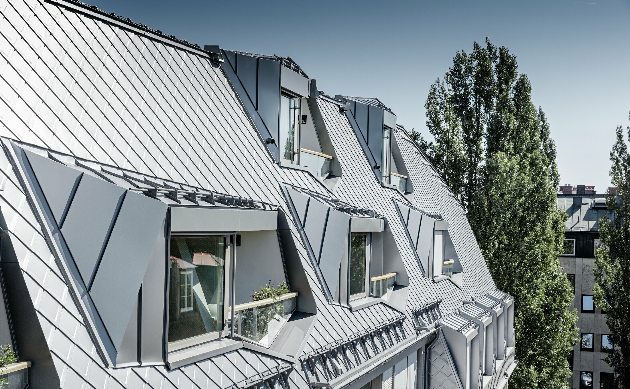 Appartements mansardés rénovés et dotés de spacieuses mezzanines, aménagés dans un immeuble d’habitation et de commerces munichois de la Leopoldstraße, à l’angle de la Hohenzollernstraße — Couverture de toit réalisée avec des losanges de toiture PREFA