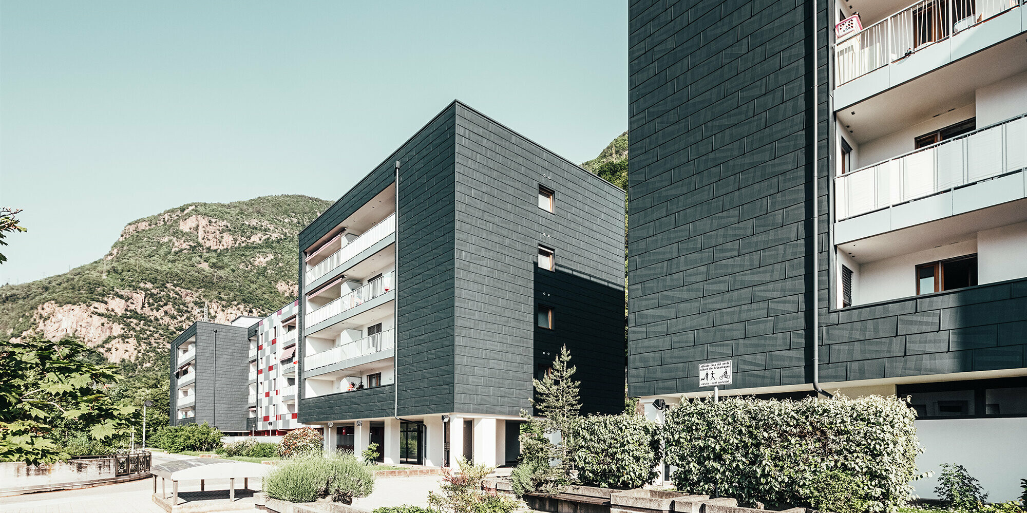 Vue de l'avancée du bâtiment rénové à Bozen. Les balcons avec leur balustrades blanches et la façade en panneaux de façade FX.12 Prefa.