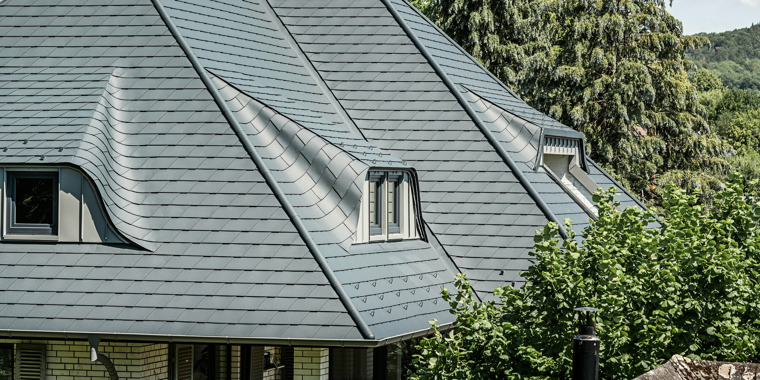 Toiture avec lucarnes cintrées d'une maison individuelle à Einbeck recouverte de bardeaux PREFA en anthracite P.10