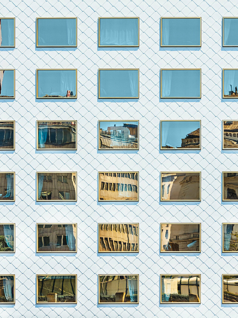 La façade de l'hôtel THE ROCK Radisson RED Vienna, conçue par INNOCAD architecture, vue en perspective normale ; on peut y voir plusieurs losanges de façade d'un blanc pur et des fenêtres à vitrage miroir qui se fondent dans l'environnement.