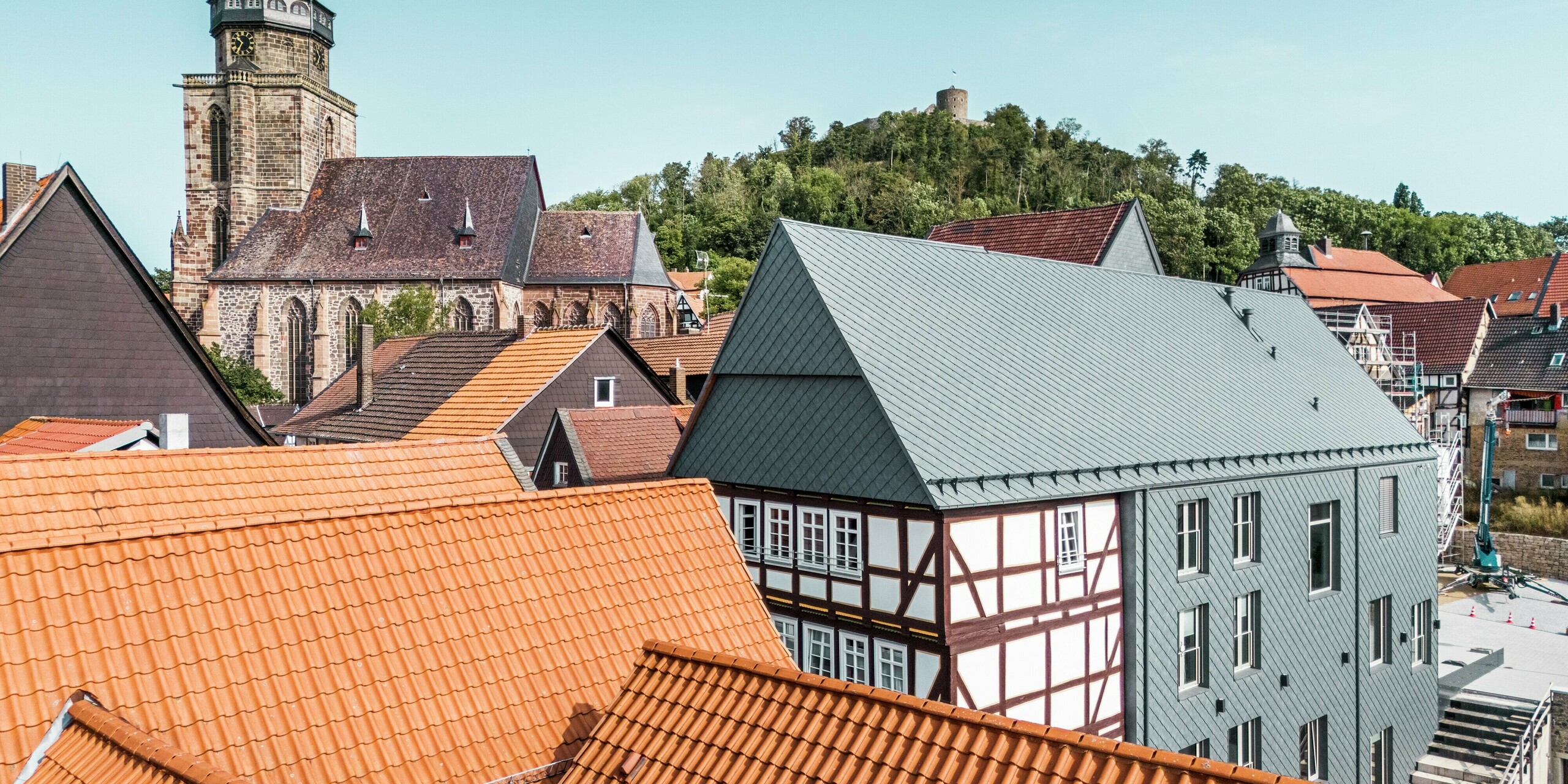 Image prise par drone du Volkshaus rénové à Homberg, en Allemagne, avec un revêtement en aluminium moderne. Les losanges de toiture et de façade 29x29 PREFAen P.10 gris pierre assurent une élégance intemporelle, une grande résistance aux intempéries et une symbiose harmonieuse avec l'environnement historique des façades traditionnelles.