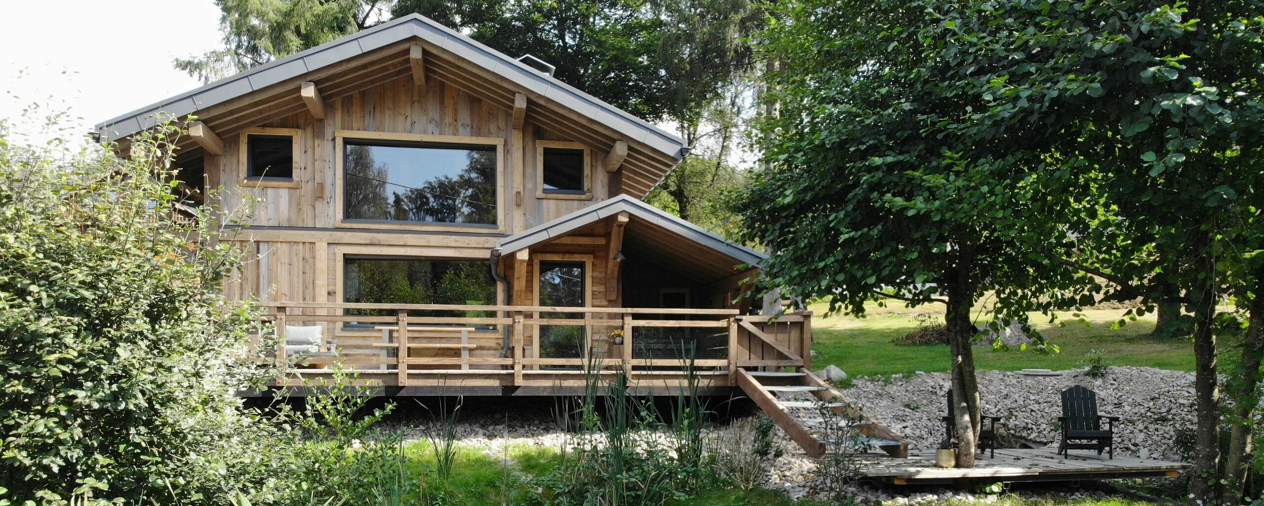 Prise de vue depuis l'étang, des nénuphars recouvrent sa surface. En fond, le gîte La Cabane à Sucre dont la couverture a été faite en R.16 PREFA