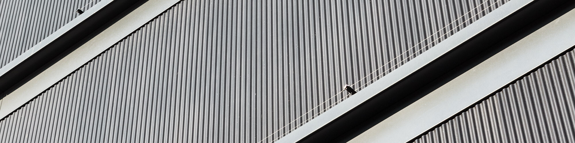 Un détail de la façade rectiligne en aluminium gris noir qui ressemble à s'y méprendre au bois de sapin blanc prégrisé utilisé.