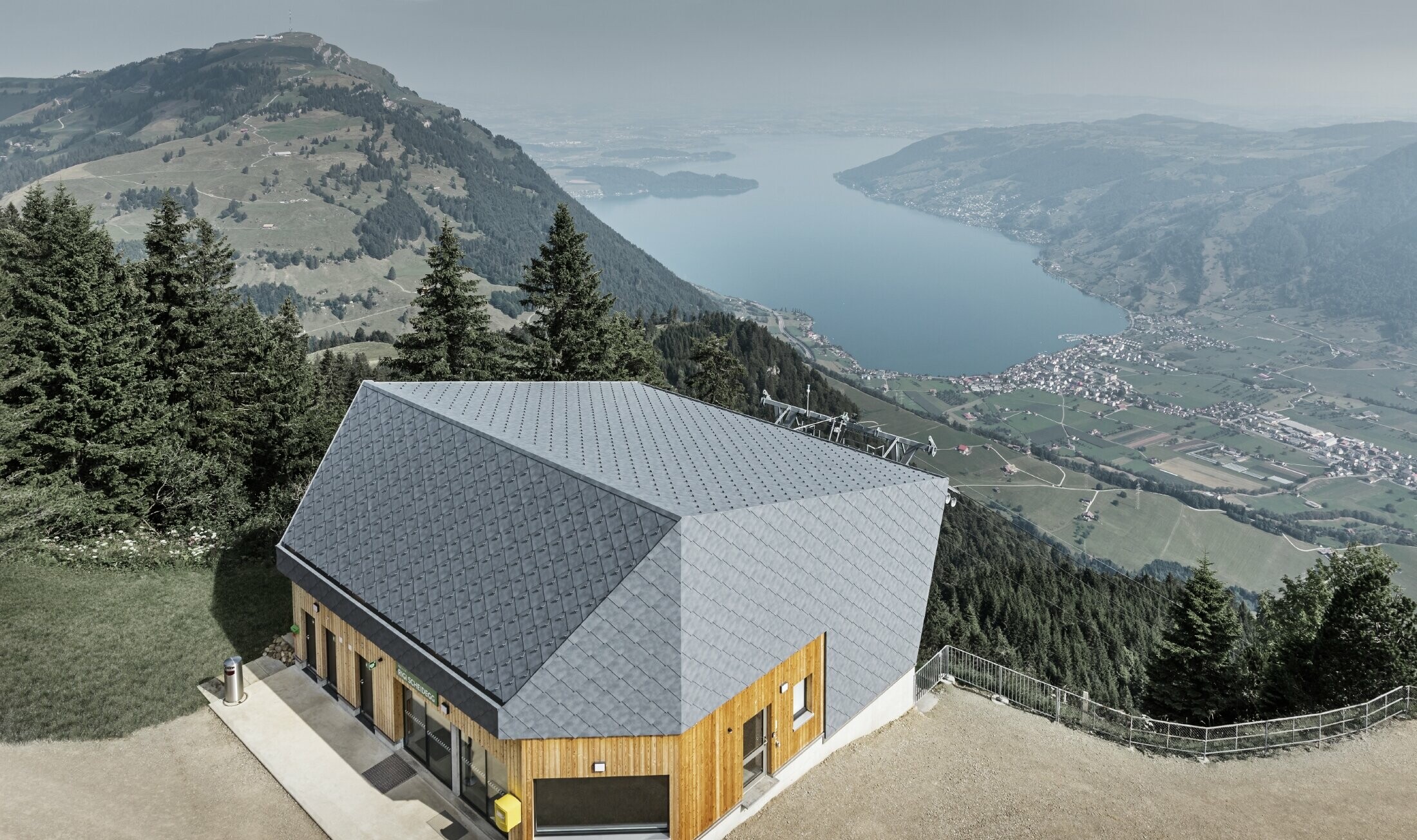 Vue aérienne de la gare d’arrivée du téléphérique du Rigi Scheidegg recouverte de losanges de façade 44 × 44 PREFA couleur P.10 gris pierre et bois.