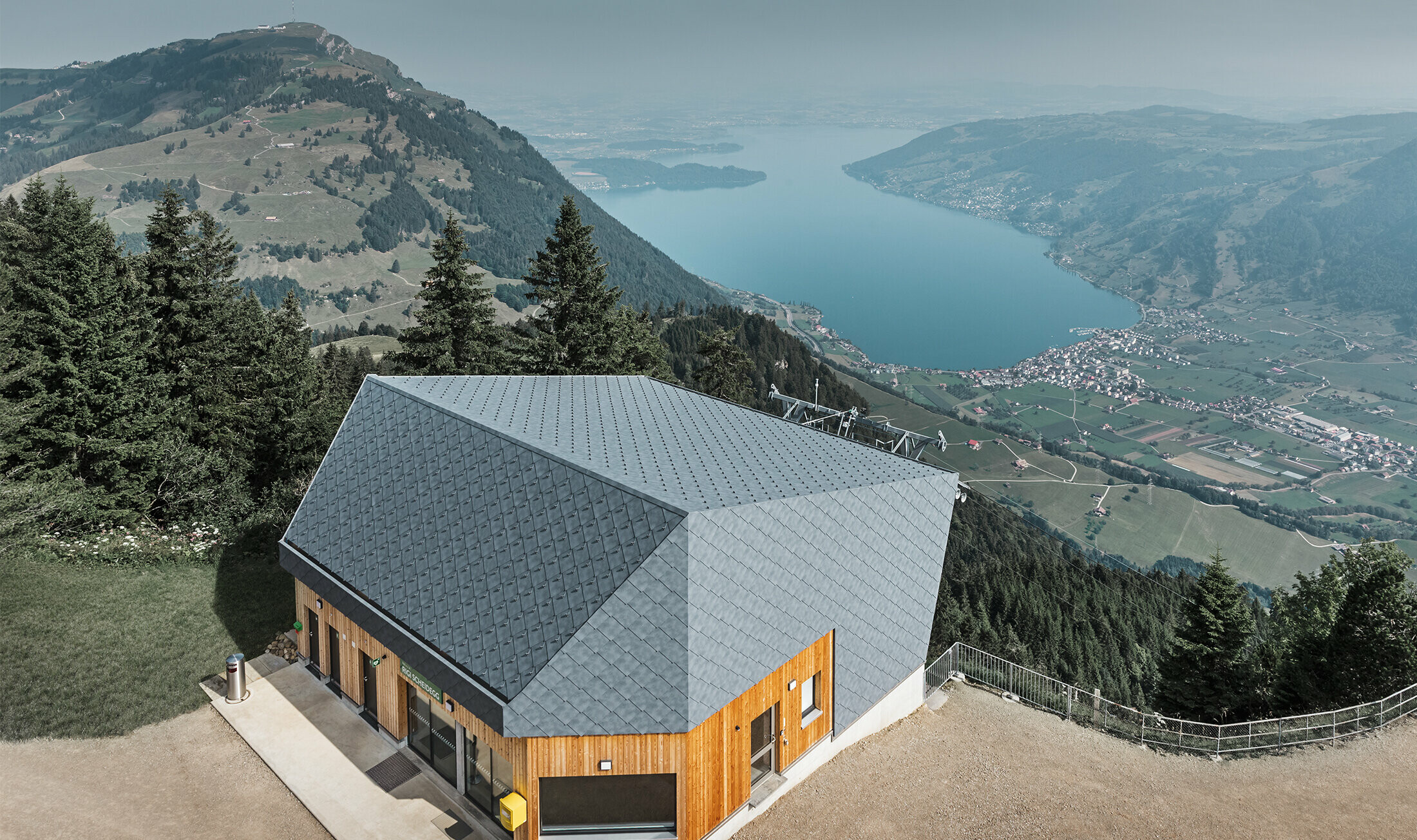 Vue aérienne de la gare d’arrivée du téléphérique du Rigi Scheidegg recouverte de losanges de façade 44 × 44 PREFA couleur P.10 gris pierre et bois.