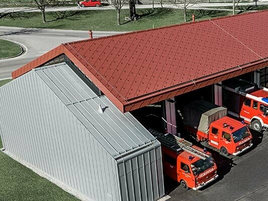 La caserne de pompiers de la société PREFA à Marktl avec sa toiture en losanges rouges doublée d’une solution à joints debout argent métallisé sur la façade et une partie de la toiture. Vous trouverez ici de plus amples informations sur les classes de réaction au feu.