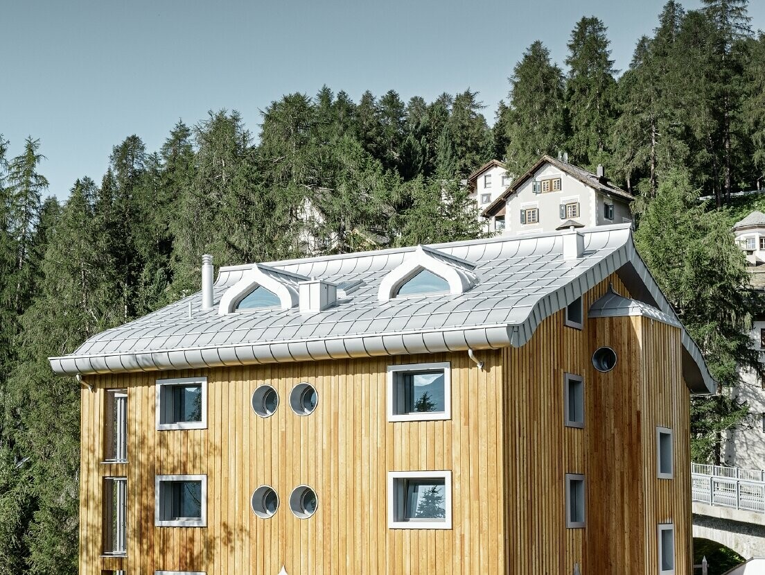 Complexe résidentiel de St. Moritz à la façade en bois — Toiture en aluminium PREFA de couleur argent métallisé avec avant-toit curviligne