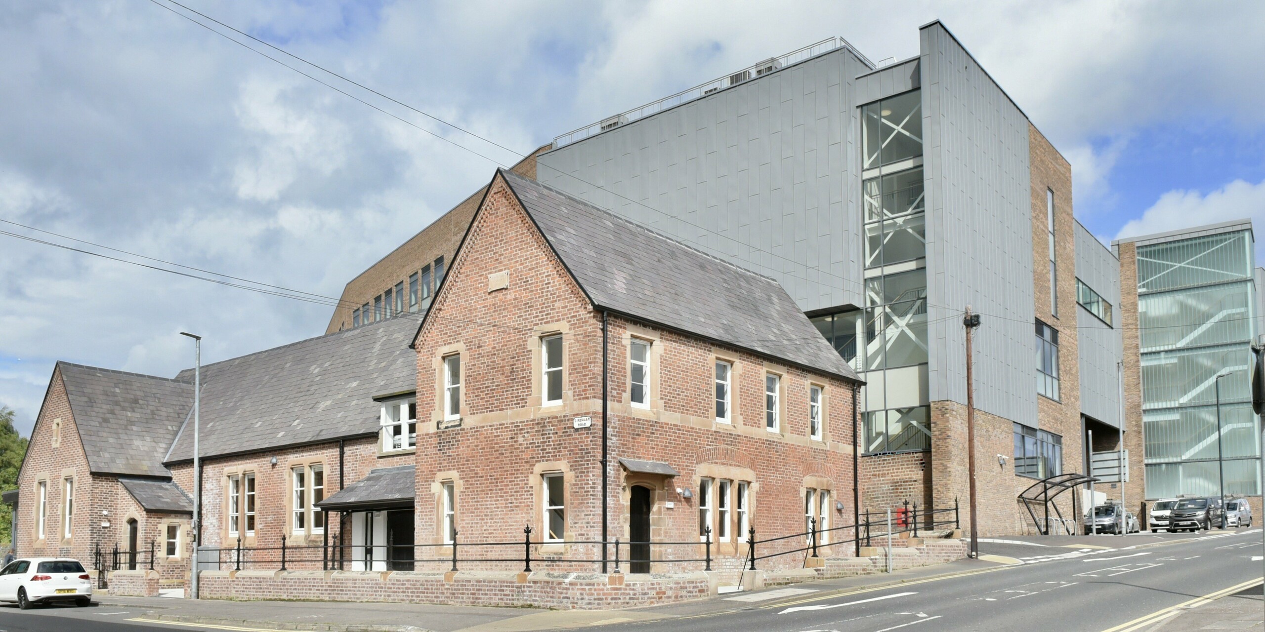 Vue de la rue du Collège Régional Nord. La combinaison de l'aluminium PREFALZ en gris quartz et des briques classiques crée une interaction harmonieuse entre modernité et tradition sur la façade du bâtiment.