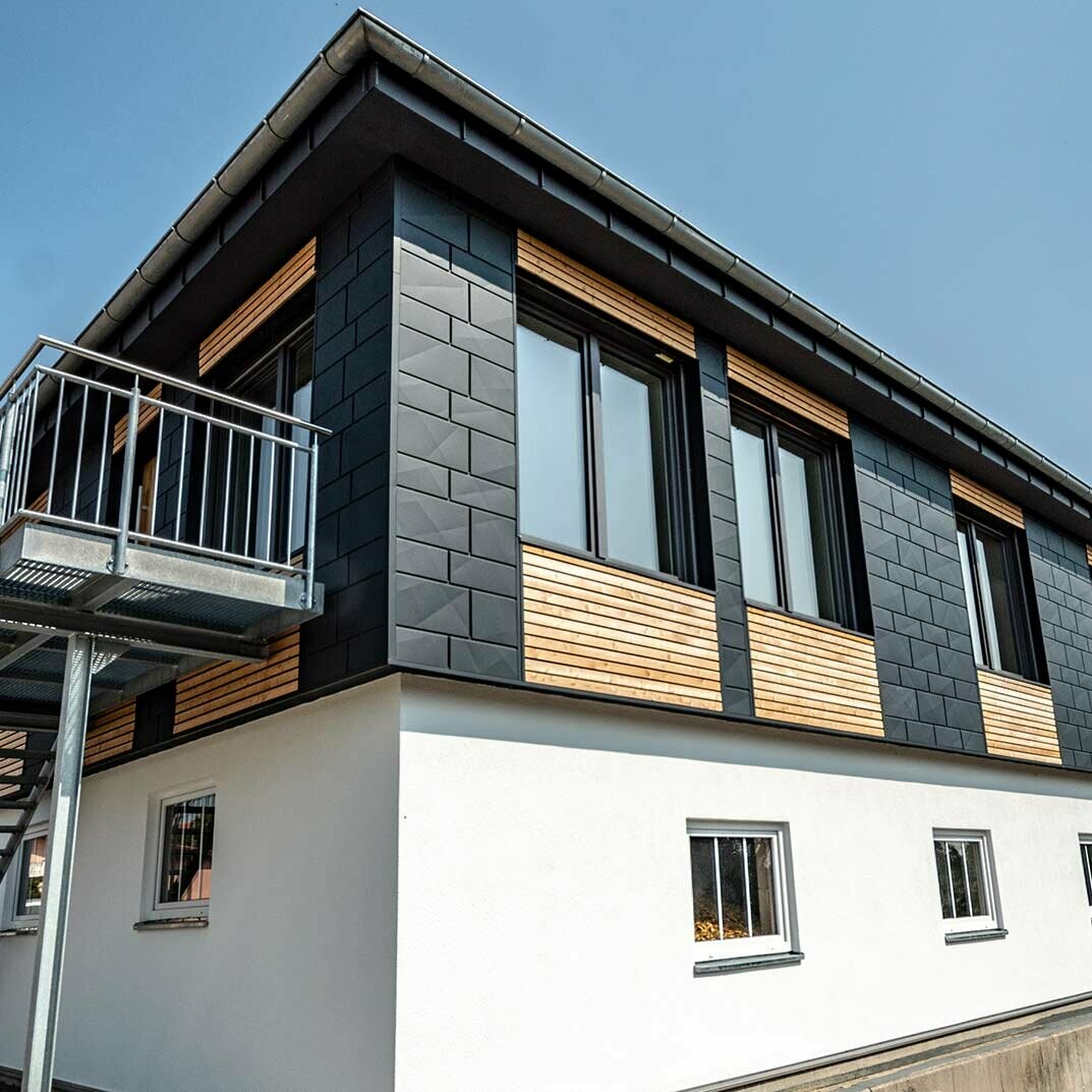 La partie haute du bâtiment a été recouverte à la fois de panneaux de mélèze posés à l’horizontale et de panneaux Siding.X PREFA en aluminium couleur anthracite.