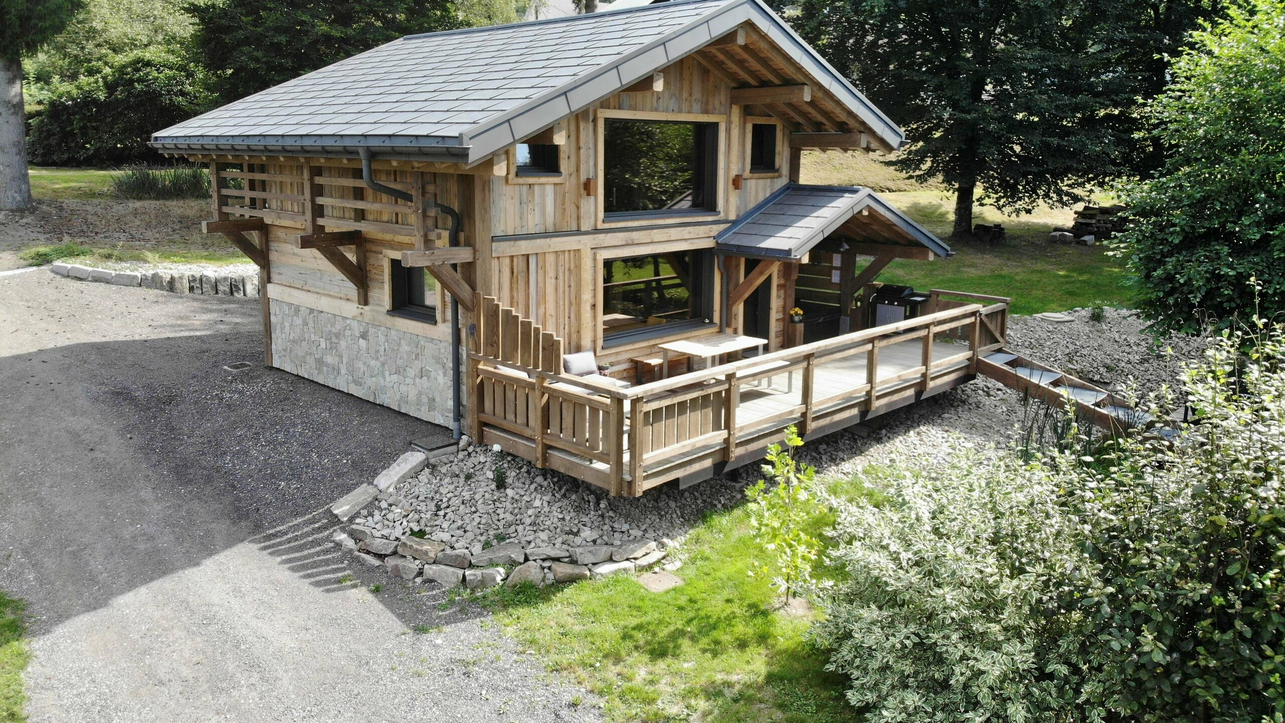 Photo de face du gîte La Cabane à Sucre où on aperçoit la grande terrasse et le spa. La toiture a été recouverte de R.16 PREFA