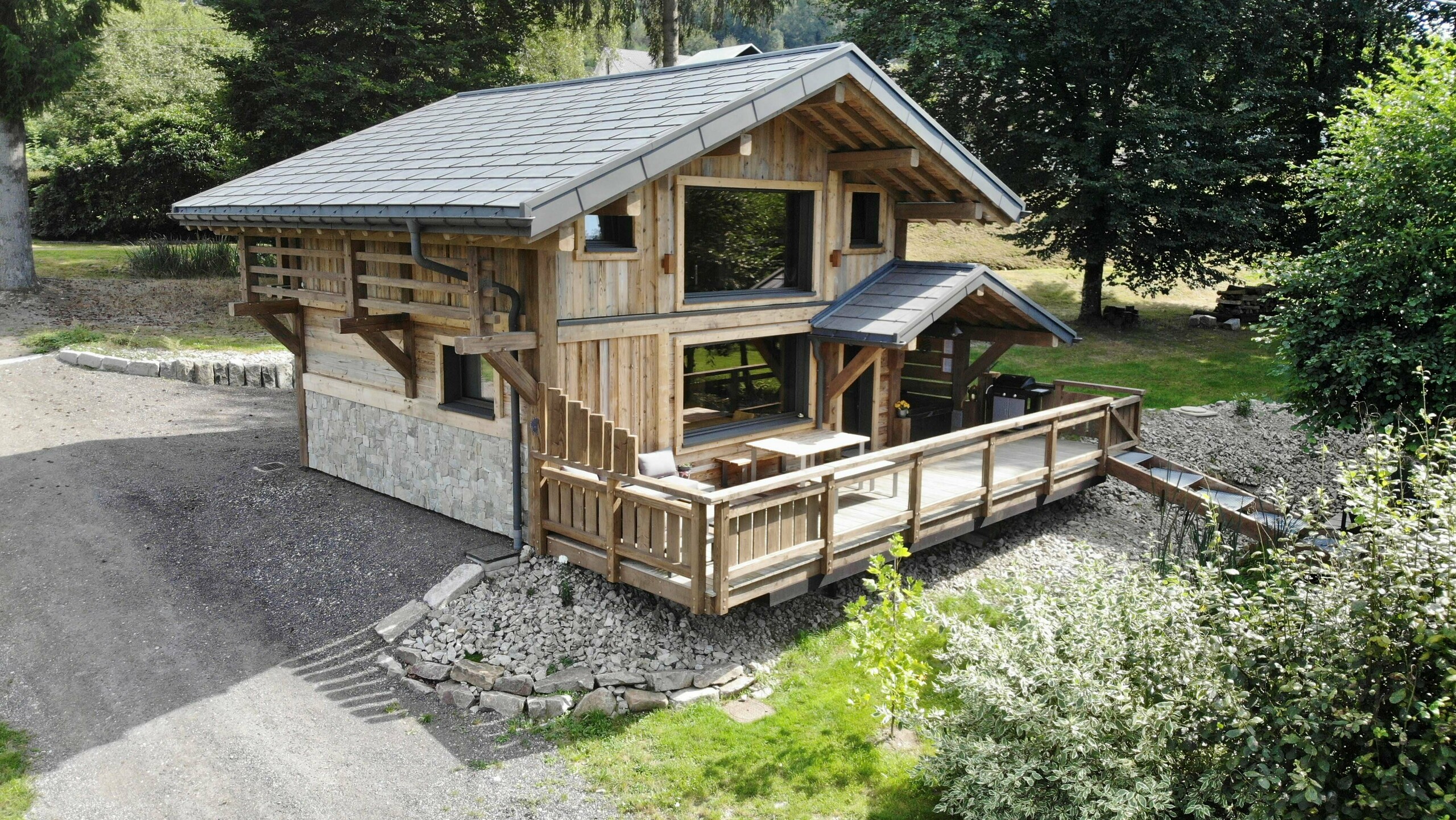 Photo de face du gîte La Cabane à Sucre où on aperçoit la grande terrasse et le spa. La toiture a été recouverte de R.16 PREFA