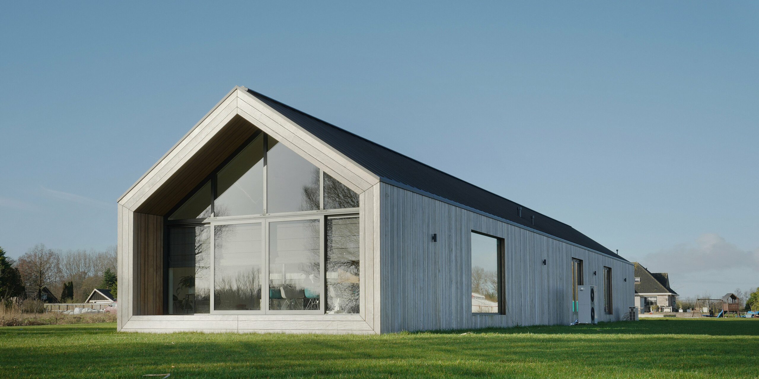 Maison familiale moderne au design d'une grange classique avec un toit PREFALZ à Uithoorn, Pays-Bas. L'architecture minimaliste combine de généreuses façades vitrées avec un toit en aluminium durable et résistant aux intempéries de PREFA. La façade en bois naturel complète parfaitement l’enveloppe du bâtiment. Le toit à pignon donne à la maison un aspect classique, tandis que les lignes épurées et le toit en tôle de haute qualité assurent durabilité et élégance intemporelle. Idéal pour les projets de construction innovants axés sur l’esthétique et la qualité.