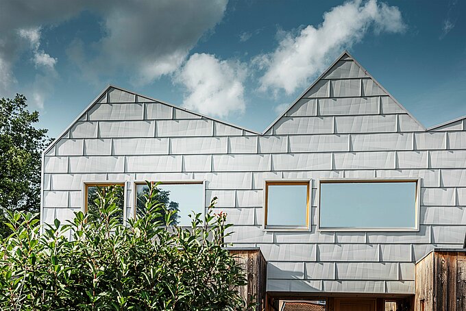 Gros plan de la façade moderne en aluminium FX.12 en blanc Prefa de PREFA sur une maison jumelée. La disposition précise des panneaux confère à la façade un aspect géométrique et structuré.