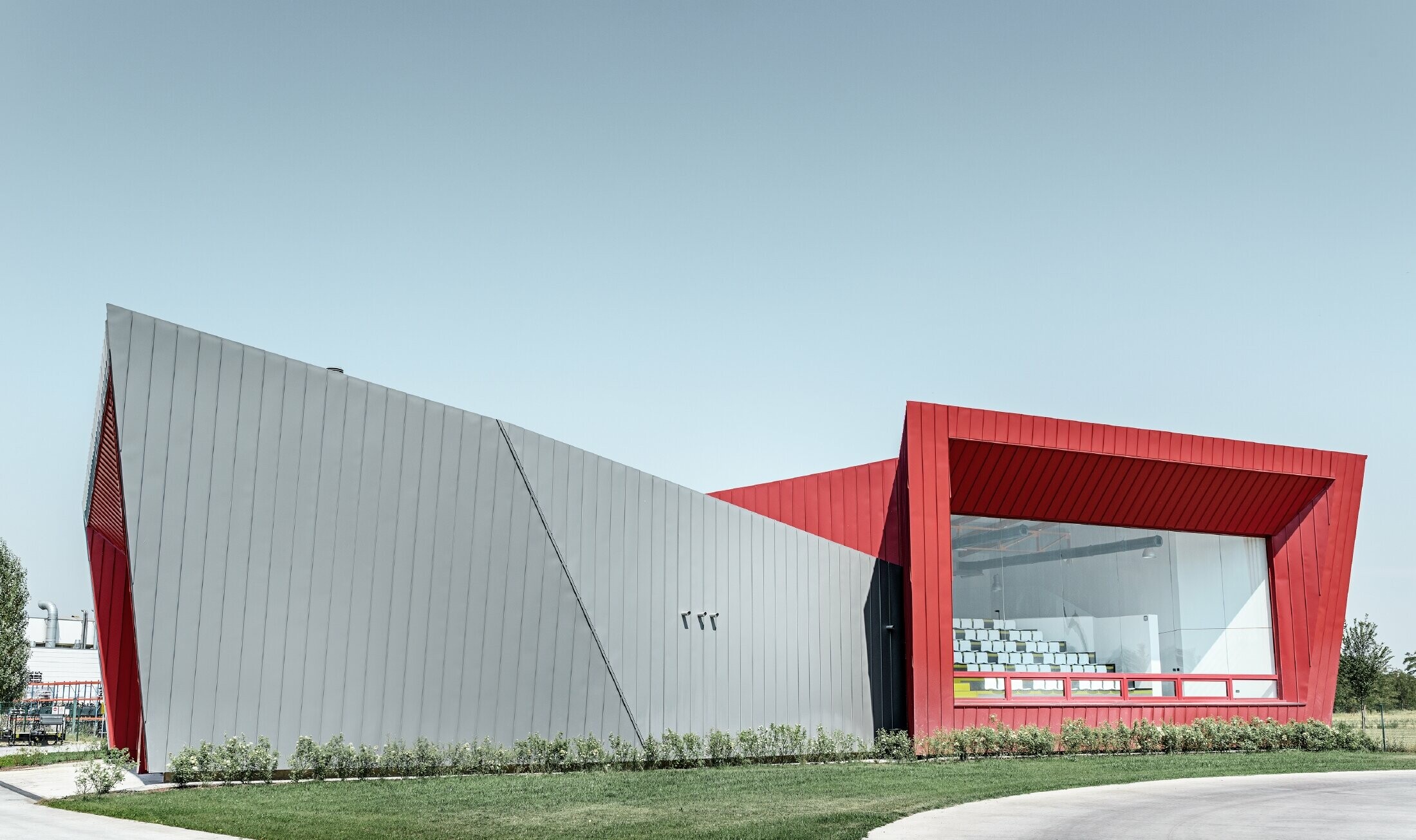 Centre d’entraînement moderne Dieci à Montecchio Emilia (Italie) — Façade des tribunes en aluminium réalisée avec des bandes Prefalz gris souris et Falzonal rouge carmin