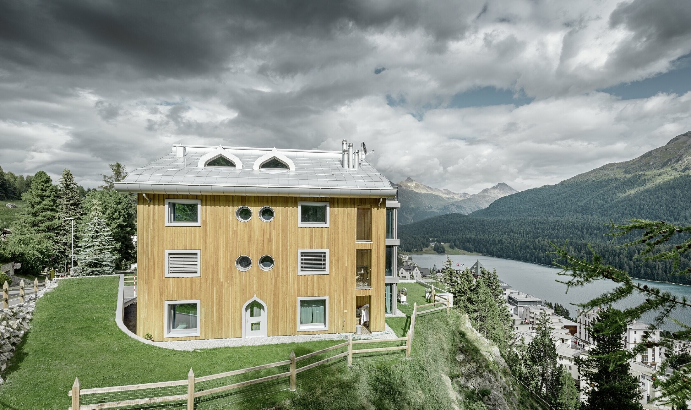 Complexe résidentiel de St. Moritz à la façade en bois — Toiture en aluminium PREFA de couleur argent métallisé avec avant-toit curviligne