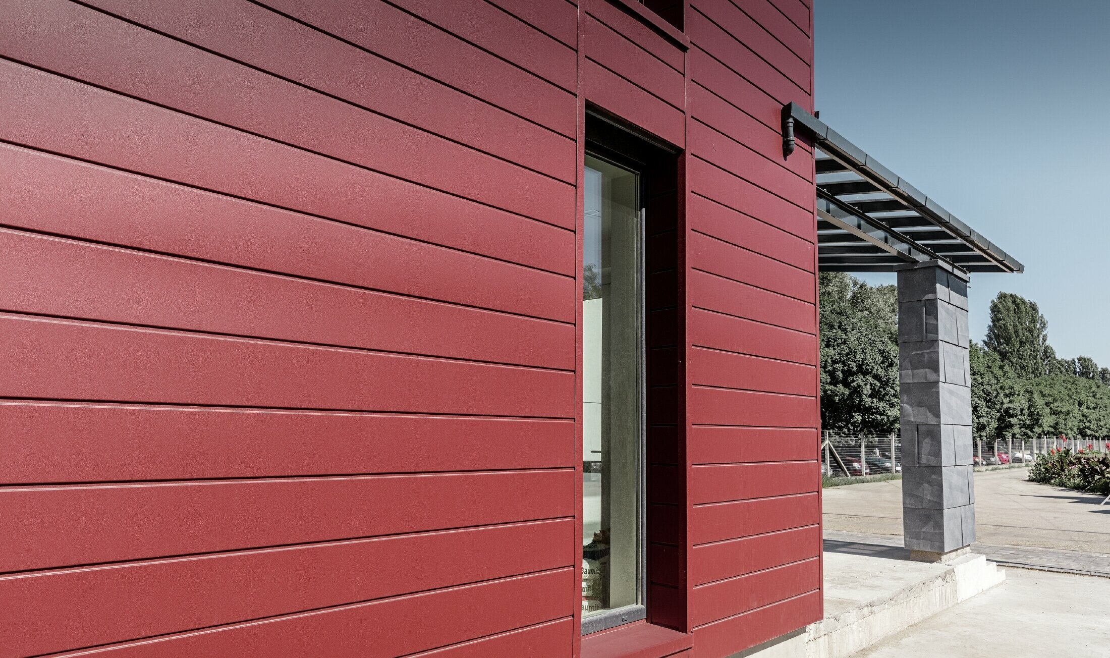 Complexe de bureaux moderne — Façade tricolore (blanc, rouge et gris pierre) réalisée à partir de produits en aluminium PREFA (sidings, panneaux de façade FX.12 et panneaux composites en aluminium)