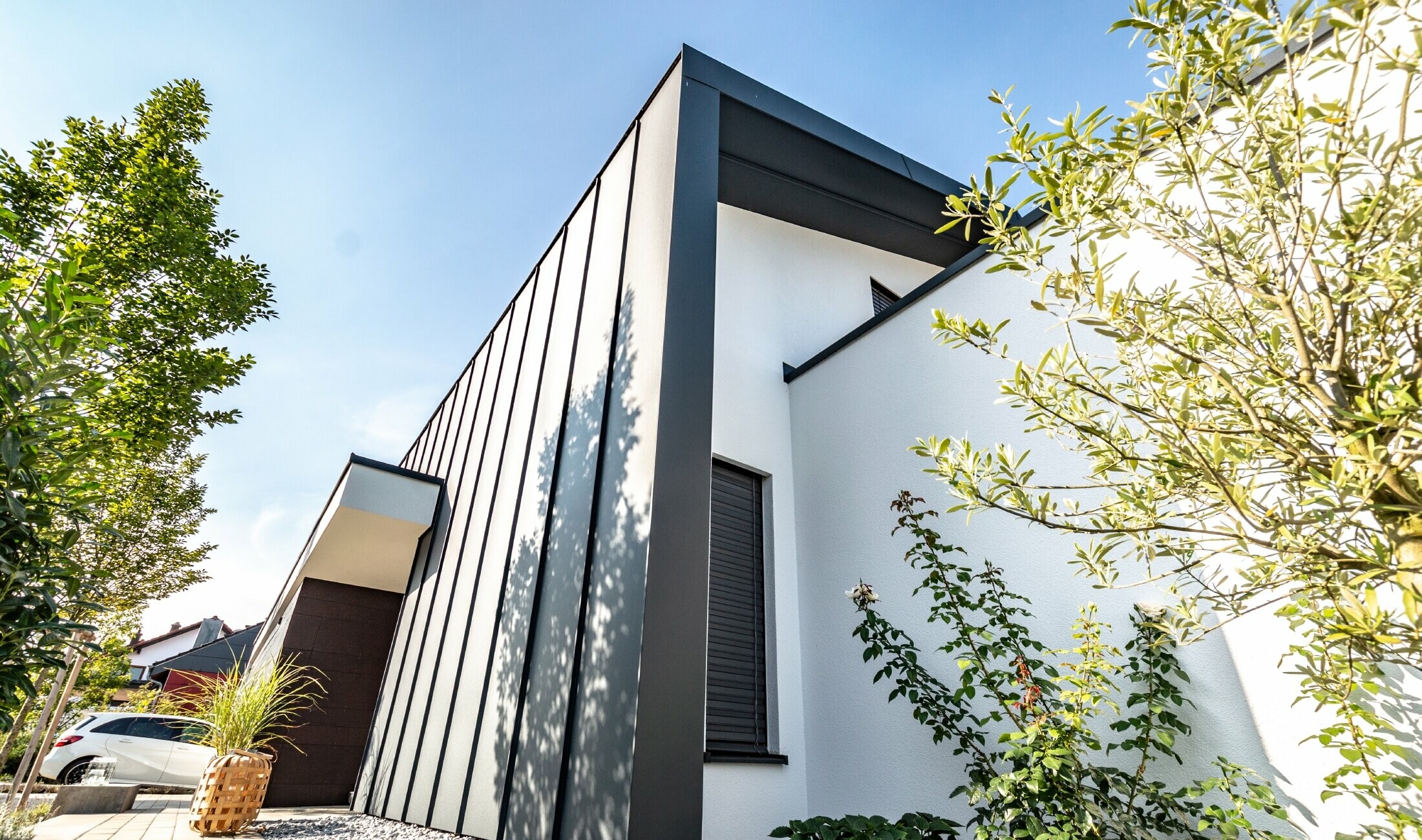 La façade Prefalz de PREFA couleur anthracite se prolonge sur le toit à deux pans de la maison individuelle.