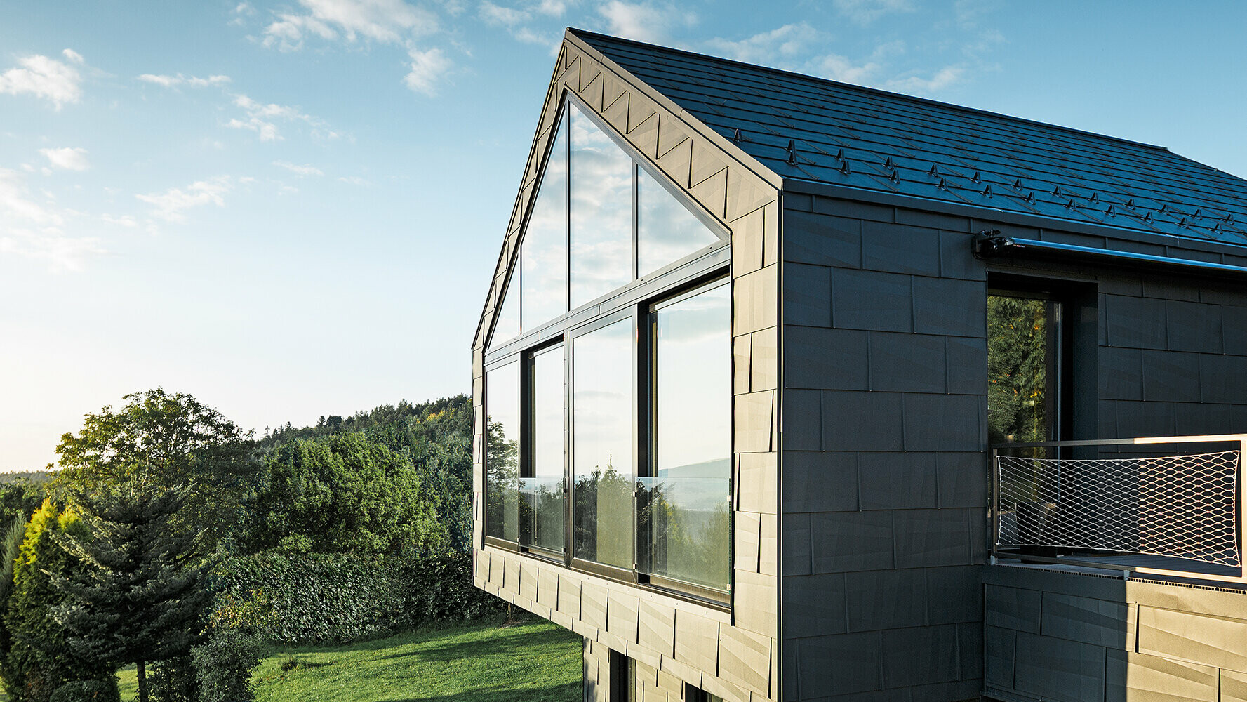 Vue de côté d’une maison individuelle moderne revêtue de panneaux de façade FX.12 PREFA couleur P.10 anthracite