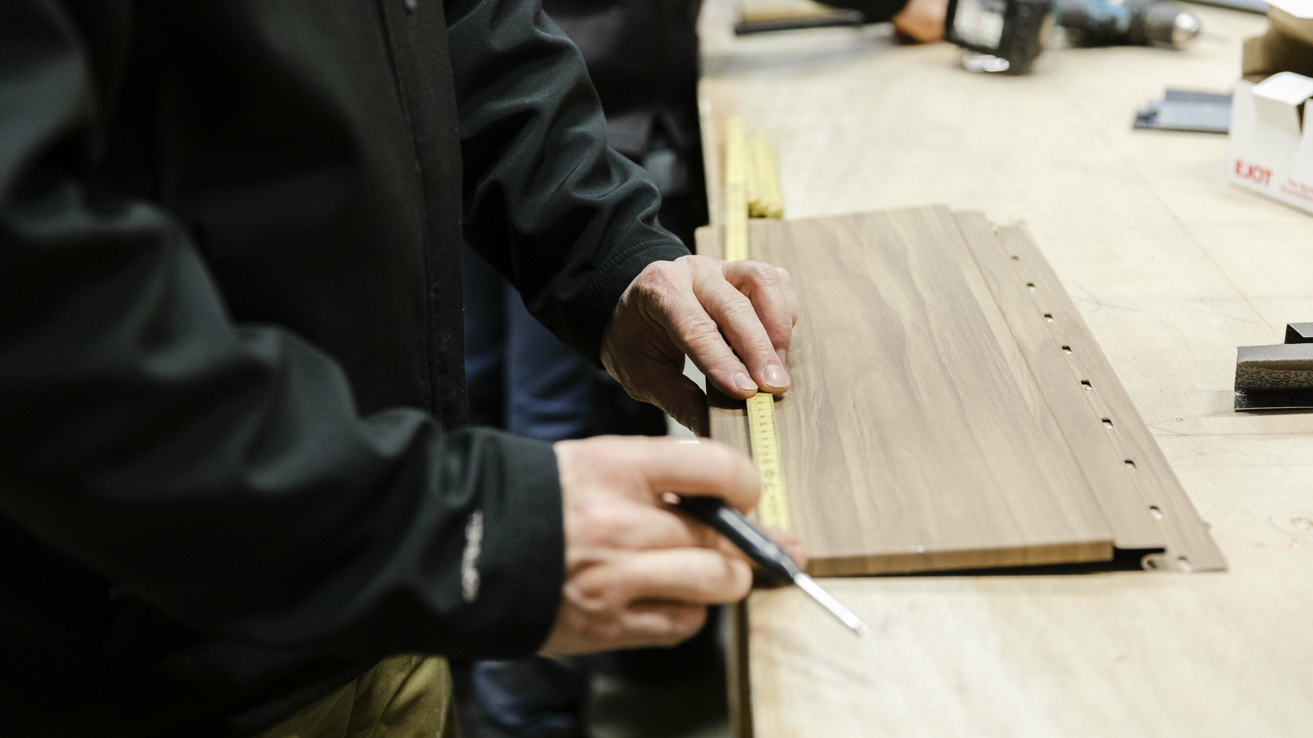 Un gros plan sur des mains ajustant une plaque de métal ondulée, dans un environnement d'atelier.