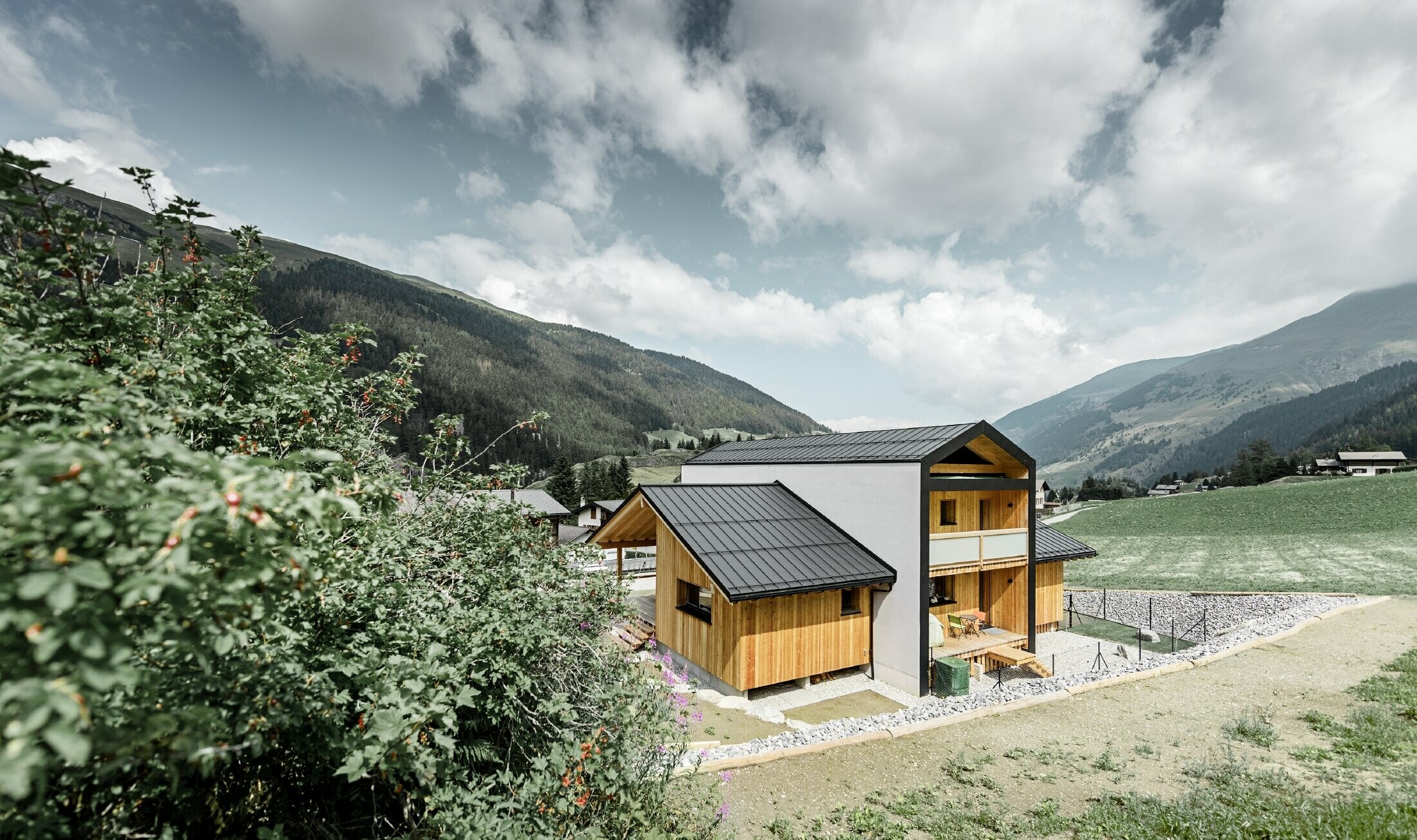 Cette maison individuelle donne l’impression que 2 maisons sont superposées selon un angle de 90°. Le toit est recouvert de Prefalz couleur noir et la façade est partiellement habillée de bois.