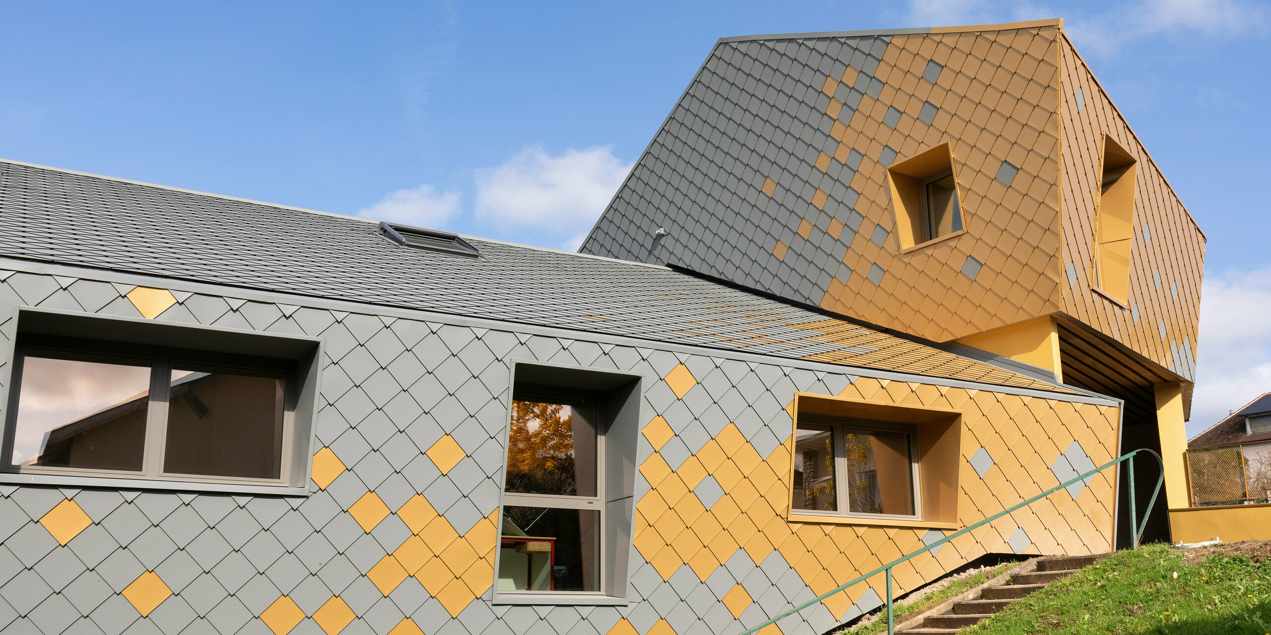 La façade de l'école primaire Jean Peyraud de Pierre-Buffière a été habillée de losanges de façade 29×29 en gris souris P.10 et or maya gold.