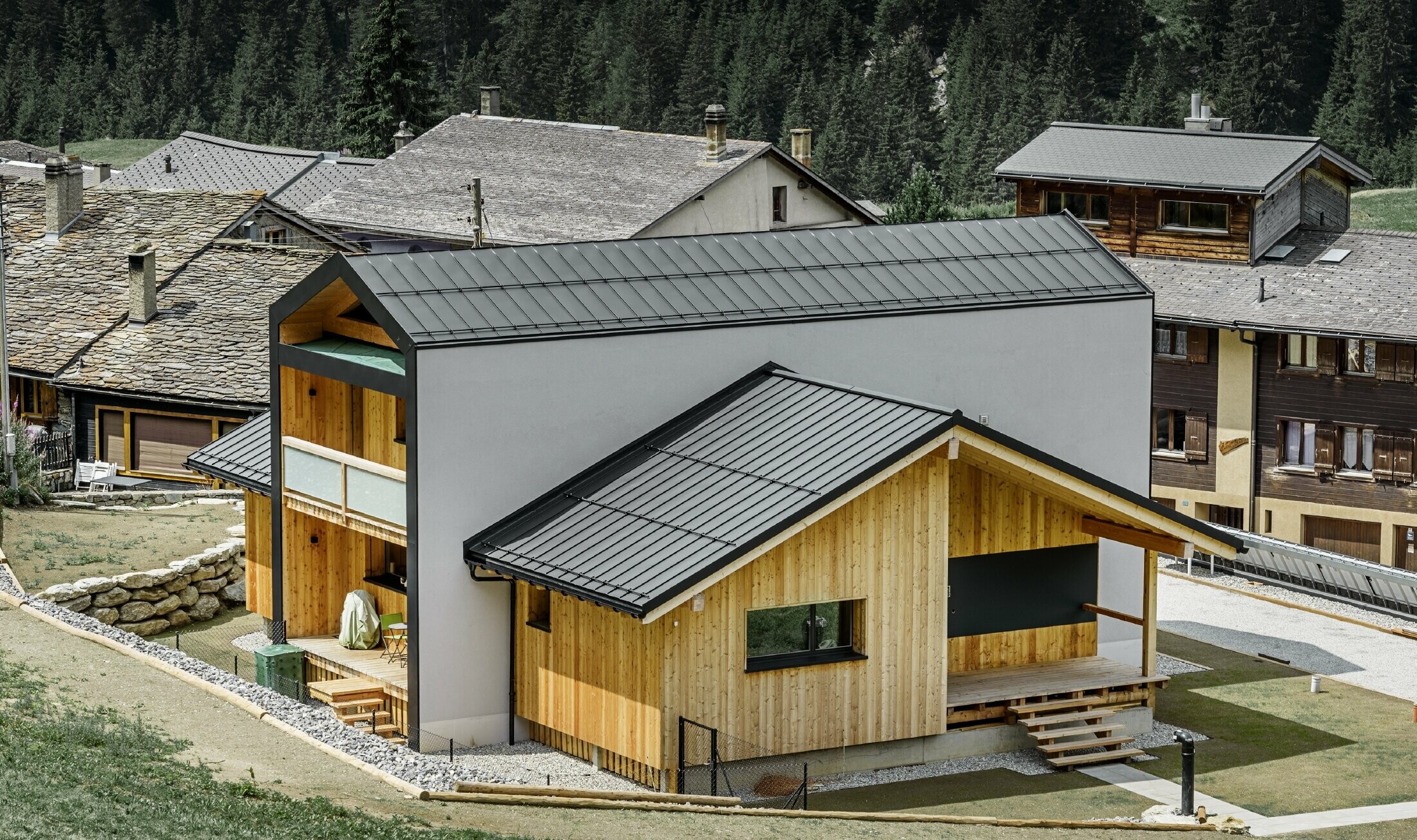 Cette maison individuelle donne l’impression que 2 maisons sont superposées selon un angle de 90°. Le toit est recouvert de Prefalz couleur noir et la façade est partiellement habillée de bois.