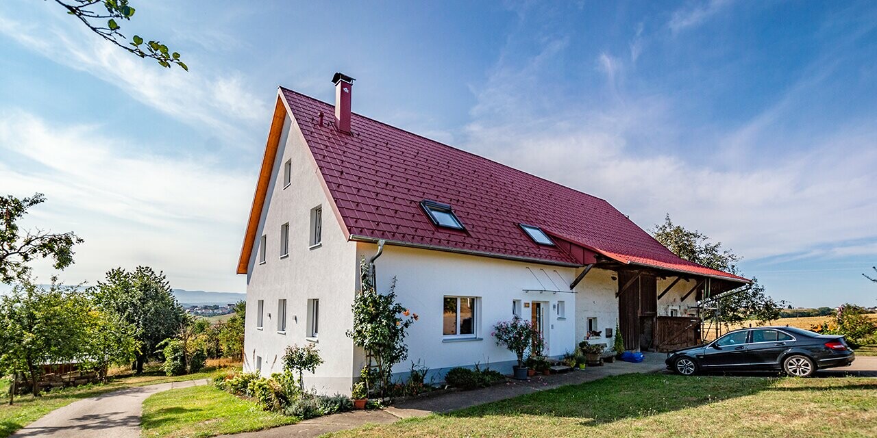 Ancienne fermette à la campagne joliment rénovée avec la tuile PREFA couleur rouge oxyde.