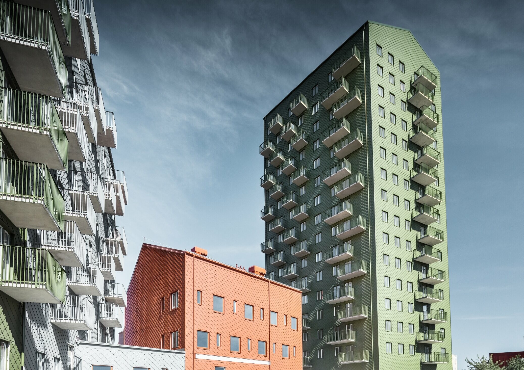 Plusieurs bâtiments d’habitation recouverts de losanges de façade 29 × 29 PREFA dans les teintes vert olive, rouge tuile et gris souris à Göteborg, en Suède.