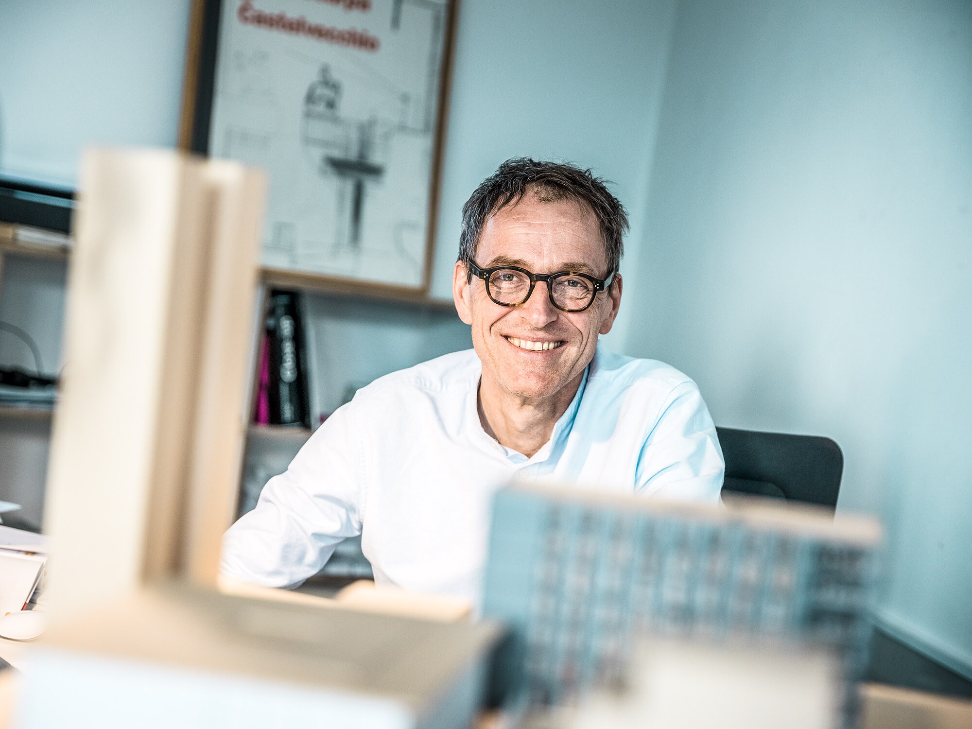 Portrait de l'architecte Jochen Weissenrieder, souriant, dans son bureau.