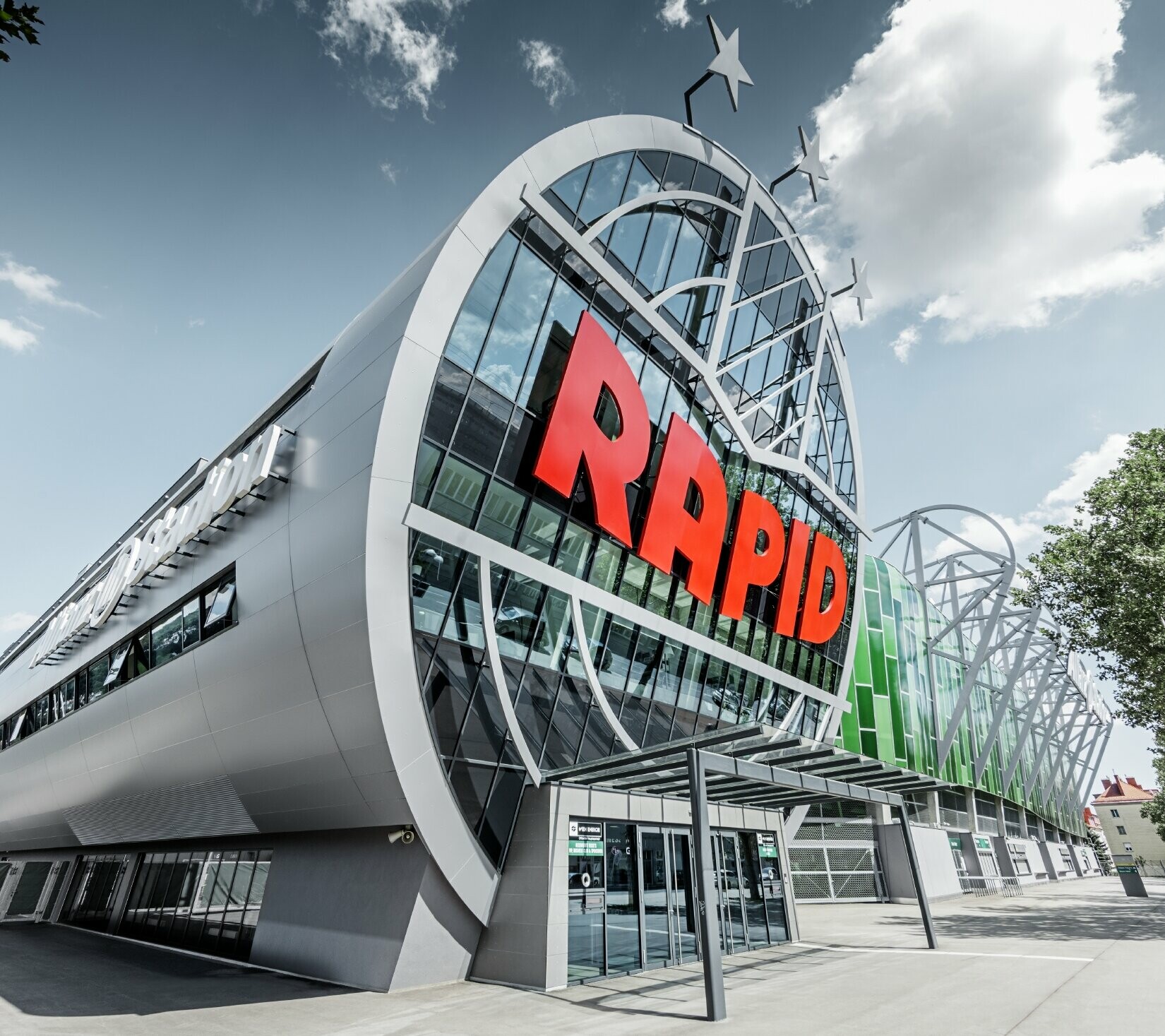 L’entrée de l’Allianz Stadion avec le grand logo du SK Rapid de Vienne ; le tube avec la grande façade vitrée est recouvert du panneau composite en aluminium PREFA couleur argent métallisé.