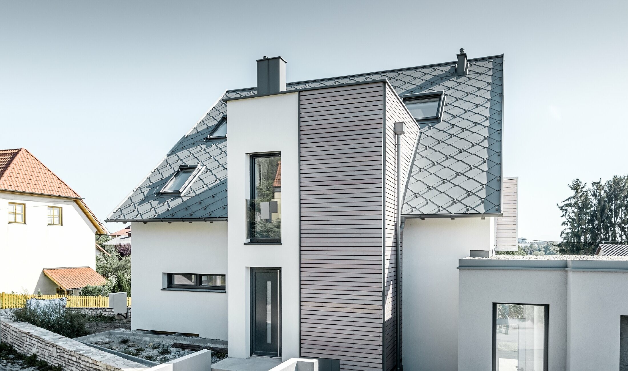 La maison individuelle avec toit à deux pans à Leonding a été entièrement rénovée. La surface de toit a été recouverte de losanges de toiture 44 × 44 PREFA couleur gris souris avec arrêts neige. Le choix s’est porté sur la gouttière suspendue de PREFA, également couleur gris souris. 