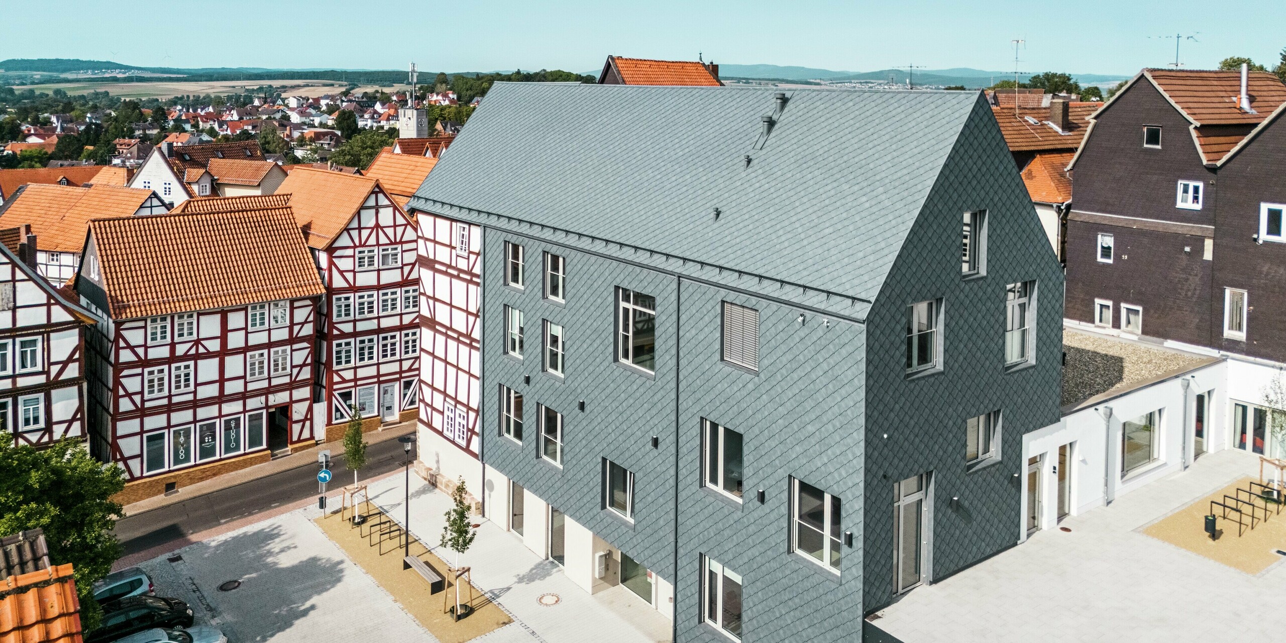 Rénovation de haute qualité du Volkshaus à Homberg, DE, intégré dans la vieille ville historique avec des maisons à colombages. La toiture, le pignon et de grandes parties de la façade sont recouverts de losanges 29x29 en aluminium PREFA robustes et élégantes en P.10 gris pierre. Le revêtement en aluminium en forme d'écailles est durable, inaltérable et s'intègre parfaitement dans l'environnement historique.