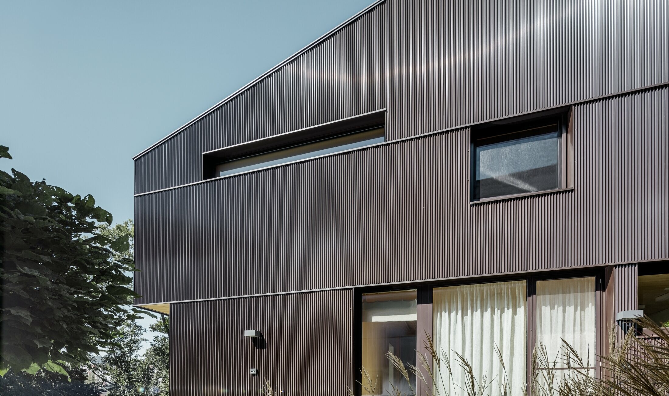 Maison individuelle moderne avec un habillage de façade en profil triangle PREFA couleur brun.