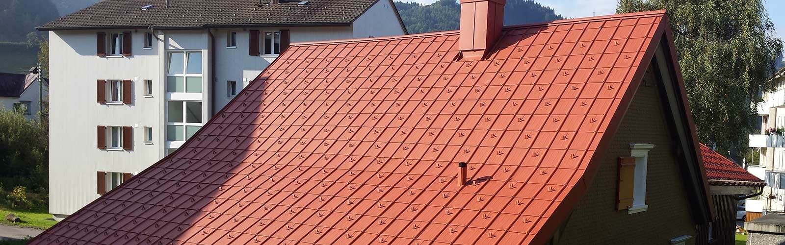 Maison individuelle avec toit à croupes à bardeaux en aluminium de PREFA imitation tuile, avec arrêts de neige.