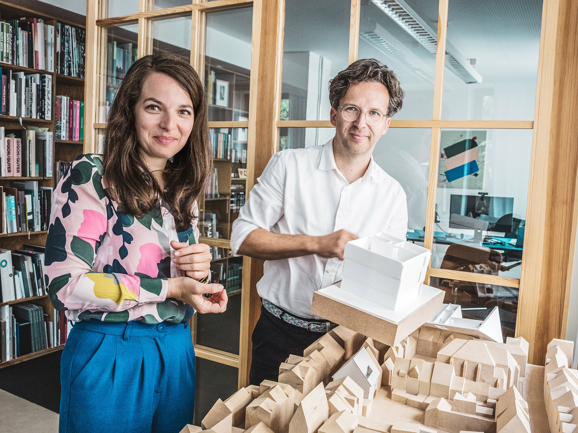 Portrait des architectes Silvia Schellenberg-Thaut et Sebastian Thaut de l'Atelier ST avec des maquettes dans leur bureau.