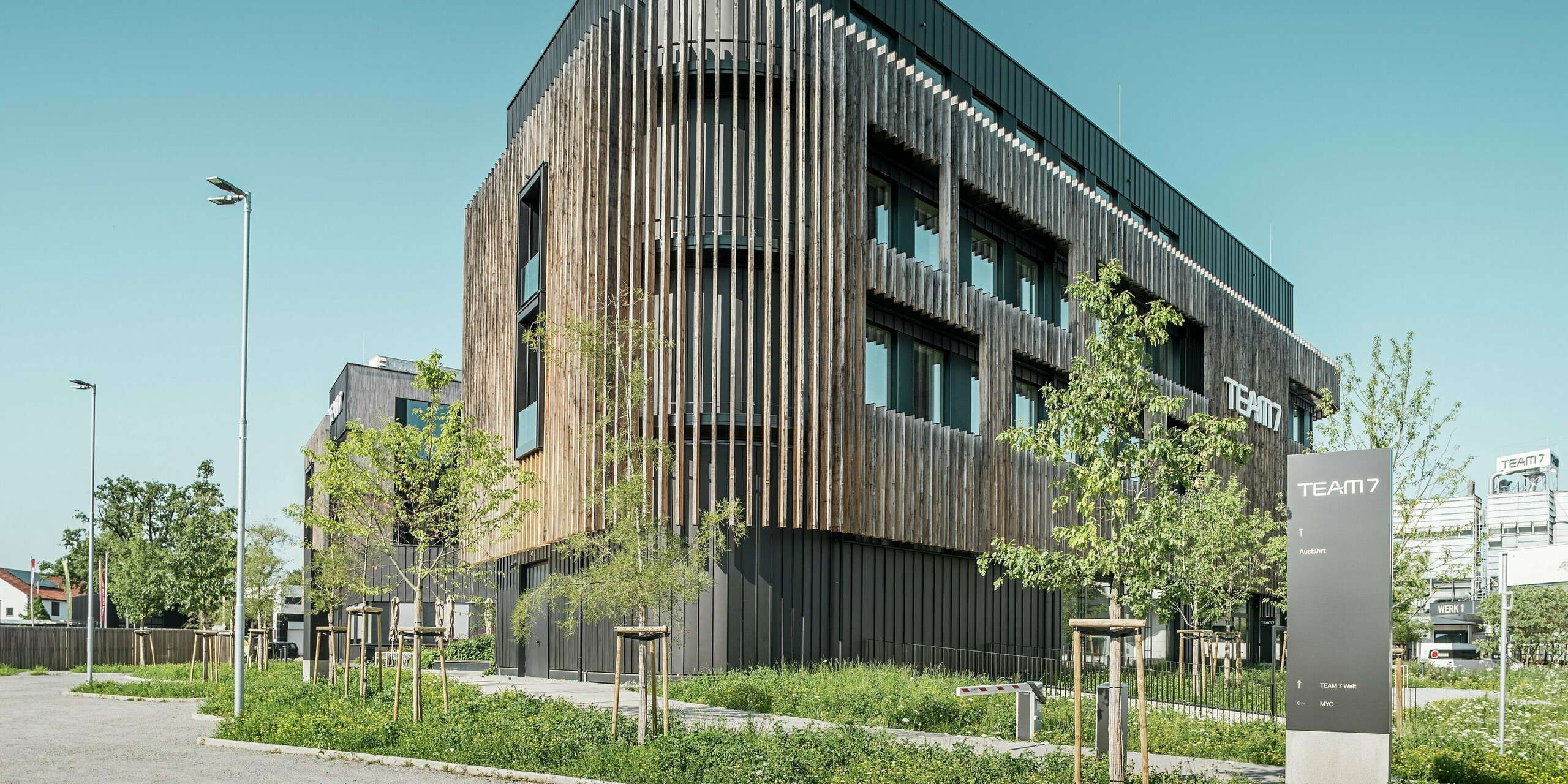 Le monde Team 7 à Ried im Innkreis vu du point de vue d'un ver montre une combinaison innovante d'une façade PREFALZ noir-brun et d'éléments verticaux en bois. L'architecture impressionnante combine un revêtement en aluminium résistant aux intempéries avec du bois naturel et est entourée d'un paysage verdoyant. Modernité, durabilité et fonctionnalité en harmonie.