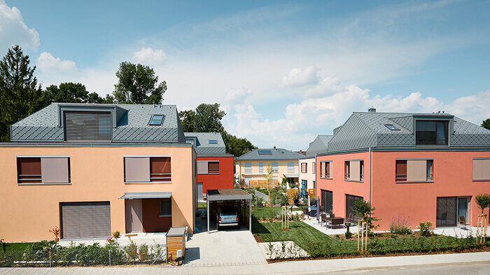 Lotissement avec façades dans les tons rouges et toits recouverts de losanges en aluminium couleur gris souris de PREFA