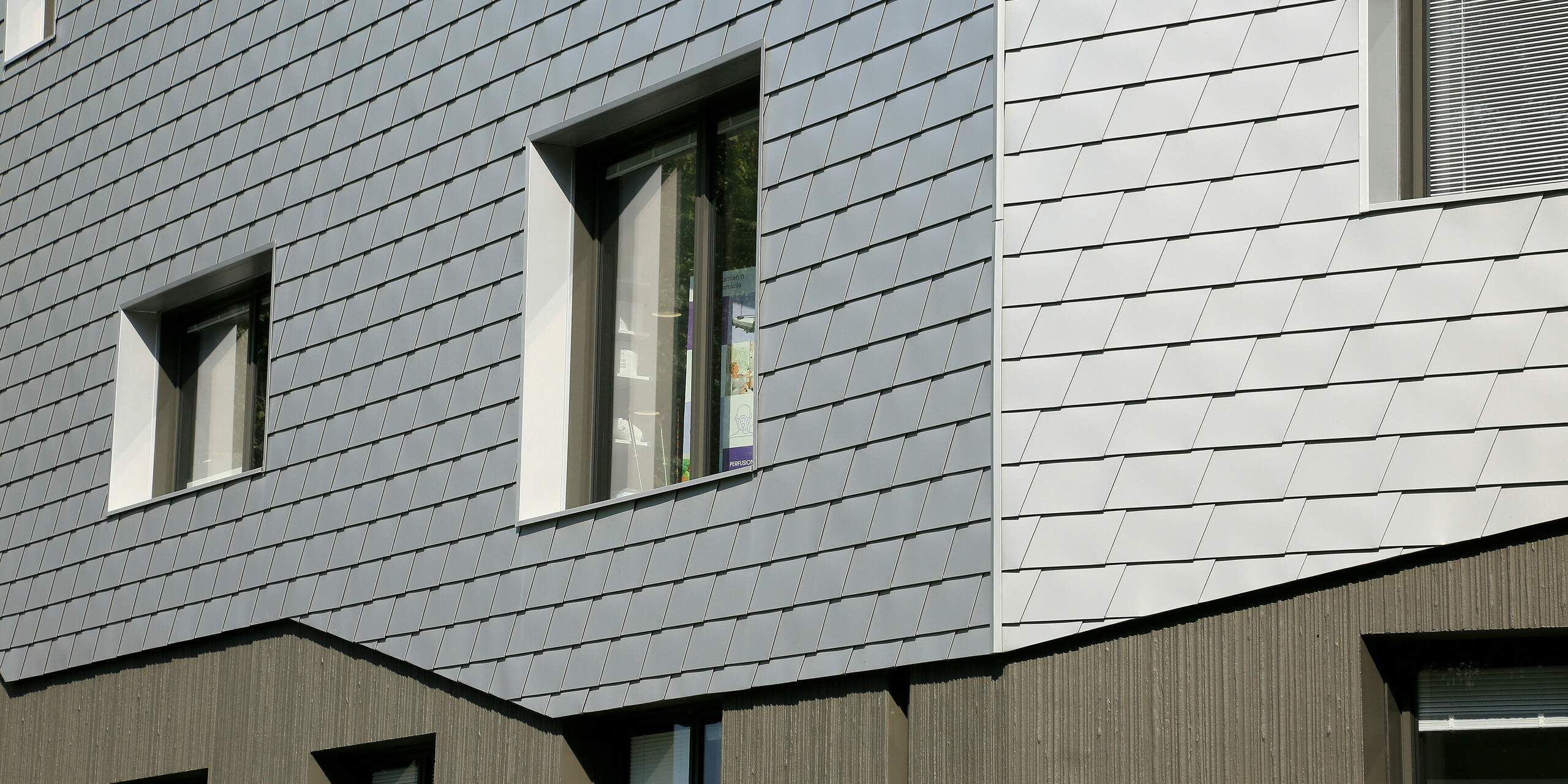 Vue détaillée de la façade du centre de santé du Landreau avec la transition de la base en béton aux bardeaux de façade PREFA en argent métallisé