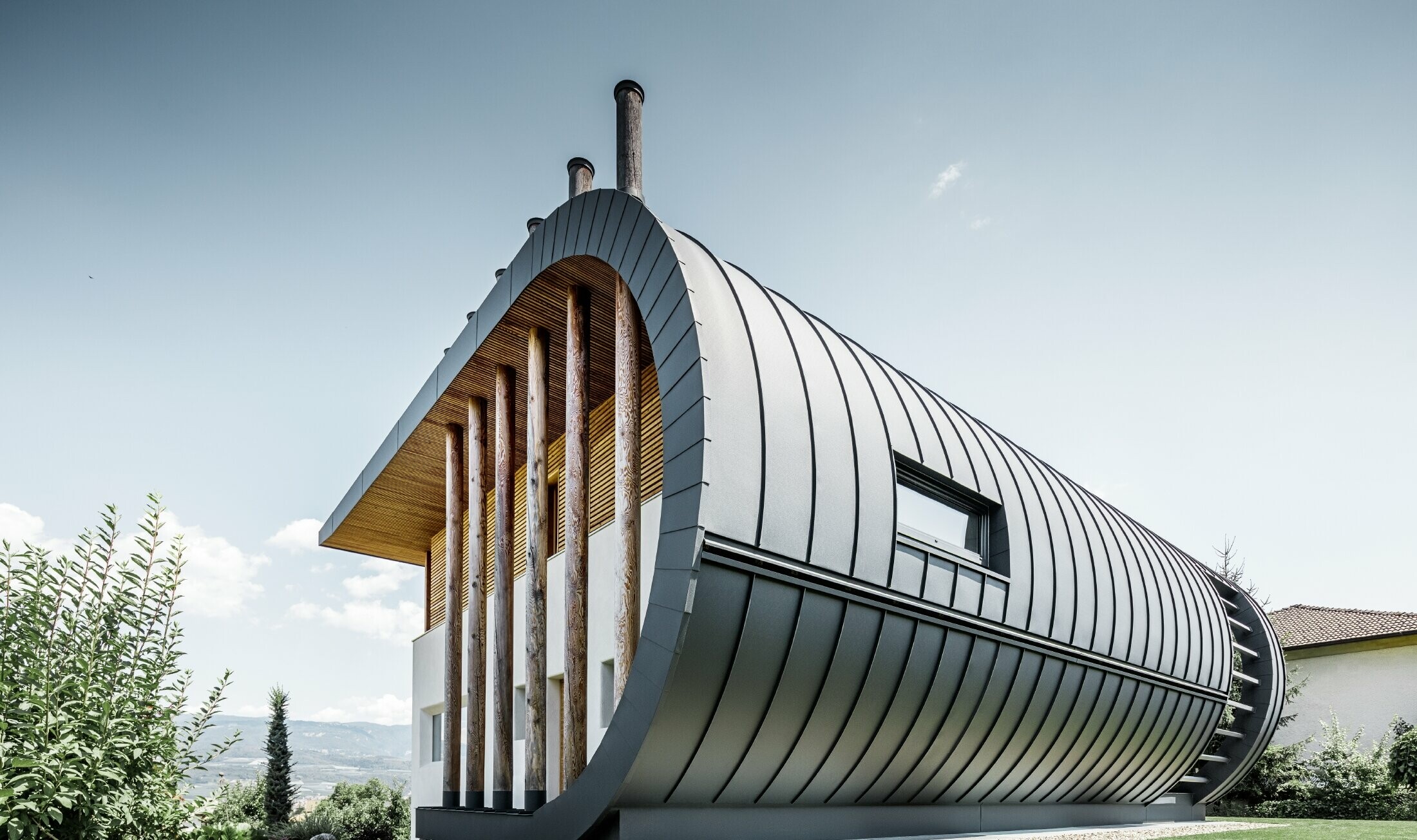 Façade courbe sur la maison individuelle Casa Giovannini recouverte d’aluminium avec Prefalz PREFA en P.10 anthracite.