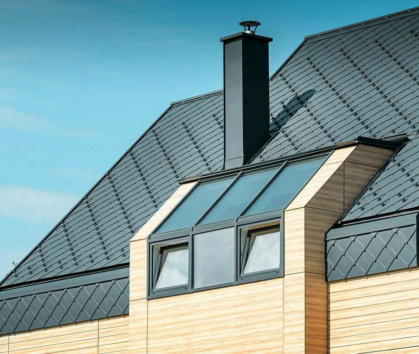 PREFA-maison-individuelle-Stanonik-losange-de-toiture02.jpg Maison individuelle au toit à deux versants sans saillie de toit — Façade à l’aspect du bois et toiture en aluminium PREFA de couleur anthracite