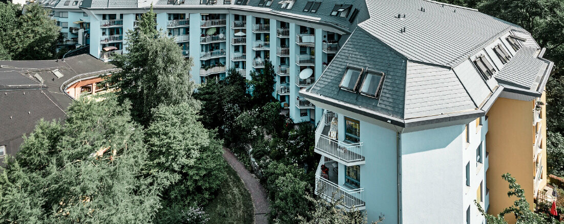 Grand bâtiment d’habitation consacré à l’accueil des personnes âgés, recouvert de bardeaux de toiture et Prefalz PREFA couleur gris pierre, avec de nombreux balcons.