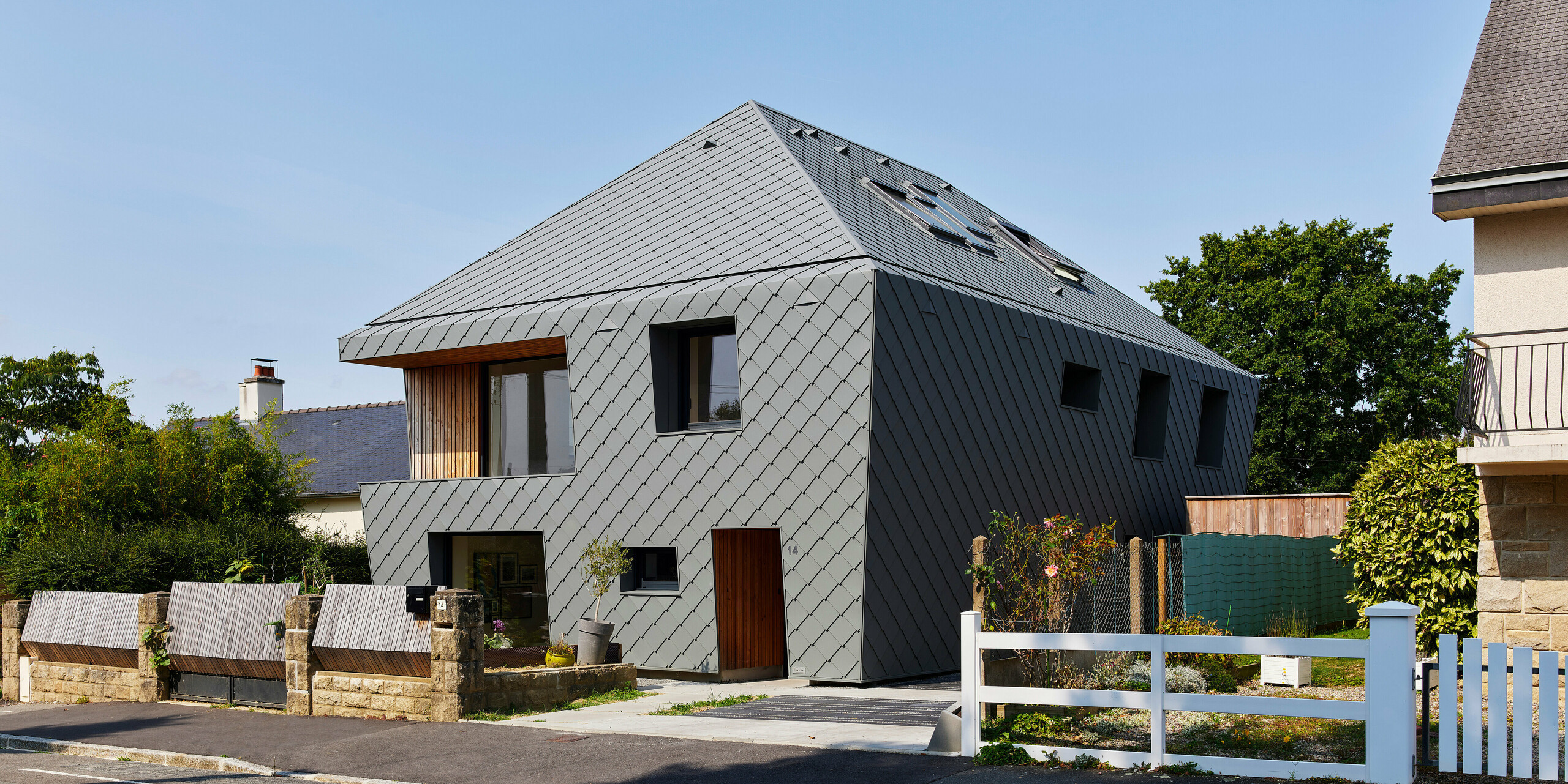 Vue oblique de la façade d'une maison individuelle à Acigne avec une enveloppe de bâtiment en losanges d'aluminium PREFA gris souris