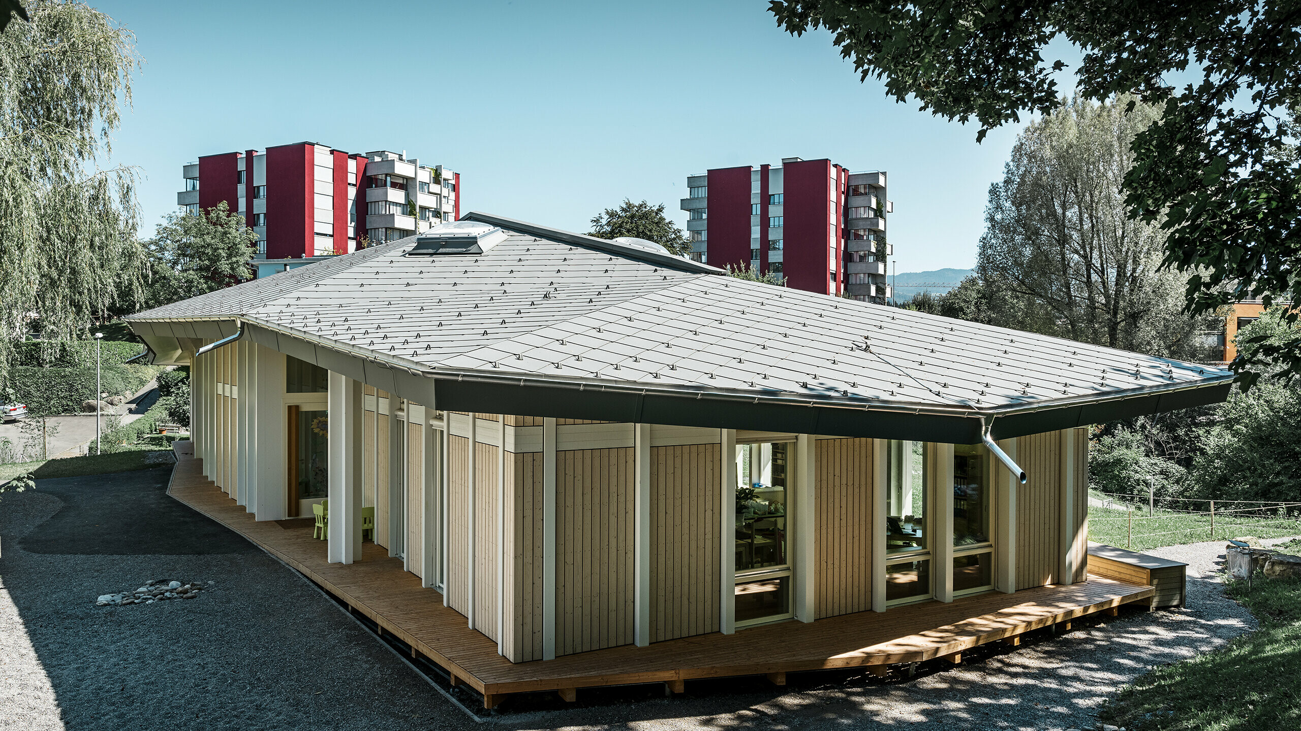 Jardin d’enfants de plain-pied avec panneaux de façade verticaux et toiture en aluminium de PREFA (losange de toiture) couleur gris souris