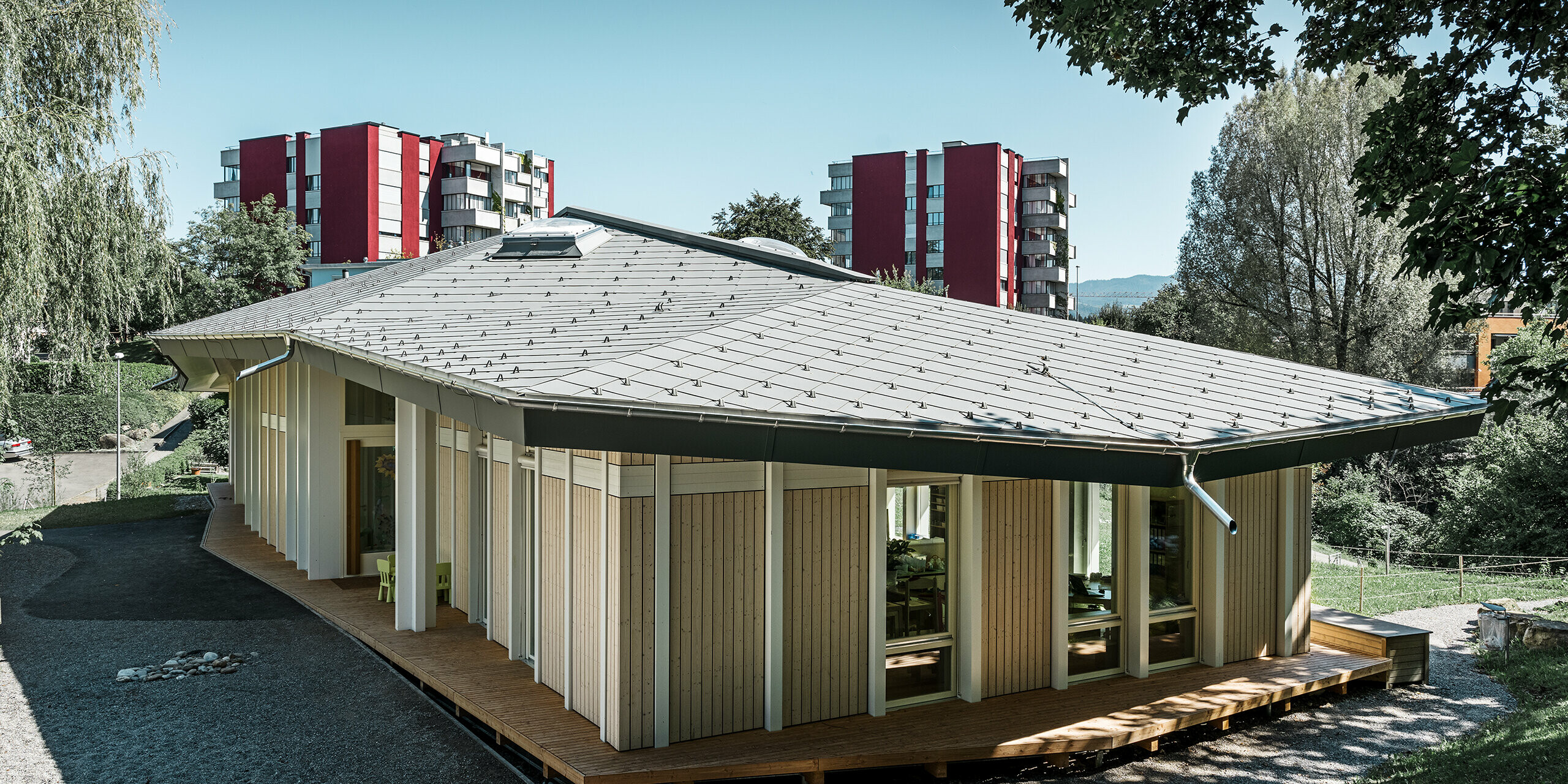 Jardin d’enfants de plain-pied avec panneaux de façade verticaux et toiture en aluminium de PREFA (losange de toiture) couleur gris souris