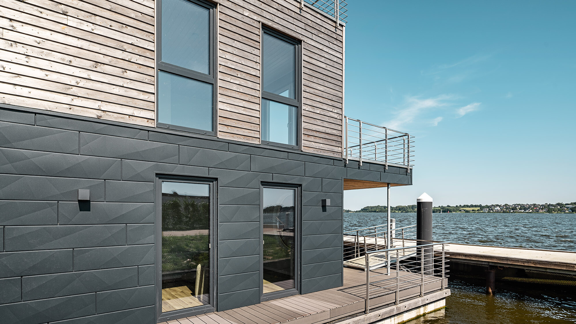 Une des maisons aquatiques vue de côté, devant laquelle s’étendent la Schlei et le ponton.